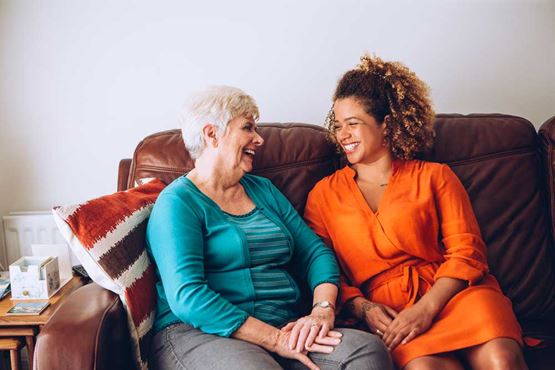 Two women laughing together on a sofa